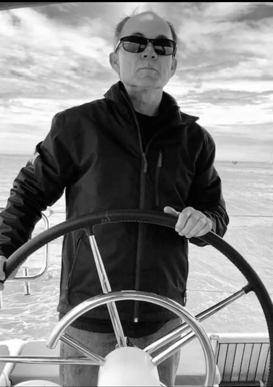 Mike at the helm of a sailboat, in black and white